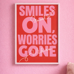 A4 poster u belom ramu sa motivacionom porukom Smiles on, worries gone u crveno-roze tonovima, postavljen na pastelno ro