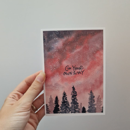 Bela art kartica sa akvarel ilustracijom crno-crvenog neba sa zvezdama i siluetom crnih stabala, sa natpisom Go Your Own