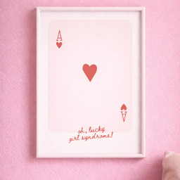A4 poster sa belim ramom sa motivom karte herc i natpisom lucky girl syndrome u roze tonovima na pastelno roze zidu.