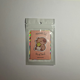 Magnet sa ilustracijom kapibare koja drži žutu zvezdu, spakovan u providnu kesicu sa holografskim ivicama.