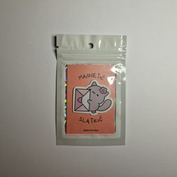 Magnet sa ilustracijom sive mace sa cvetićem na glavi koja sedi pored kovertice sa srcem, spakovan u providnu kesicu sa