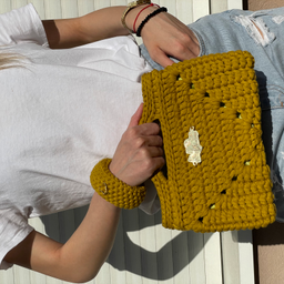 Model nosi ručno rađenu heklanu torbu u senf žutoj boji sa narukvicom, uklopljenu uz casual outfit – bela majica i svetl